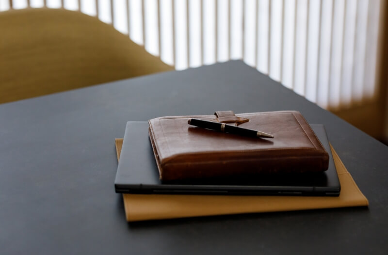 机に置かれた茶色いカバーの手帳とペン